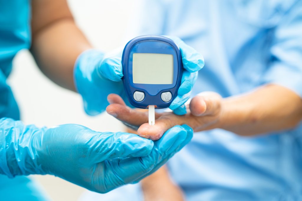 Doctor check diabetes from finger blood sugar level with finger lancet.